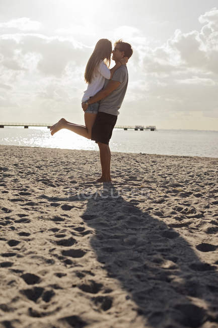 Uomo che trasporta donna in spiaggia — Foto stock