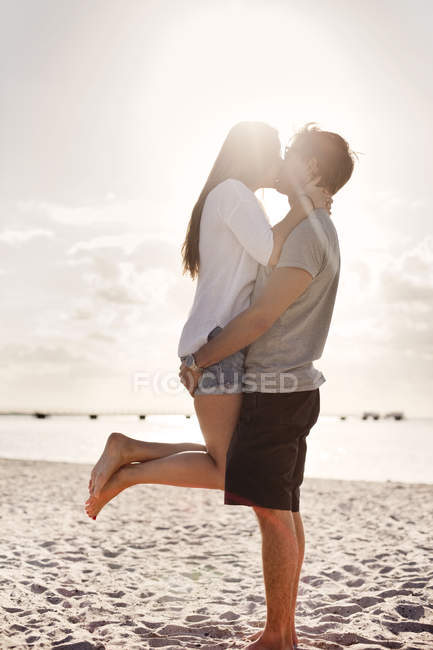 Homme portant femme à la plage — Photo de stock