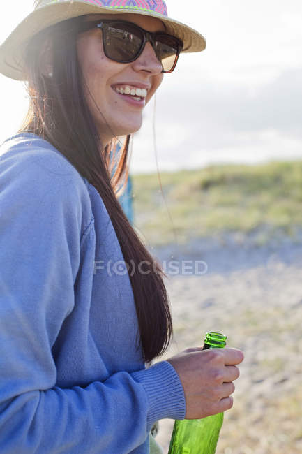 Donna che tiene bottiglia di birra in spiaggia — Foto stock