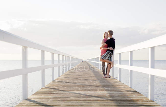 Junges Paar küsst sich auf Seebrücke — Stockfoto