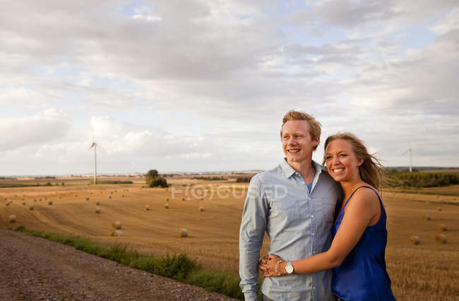 Пара тримає руки, стоячи на полі — стокове фото