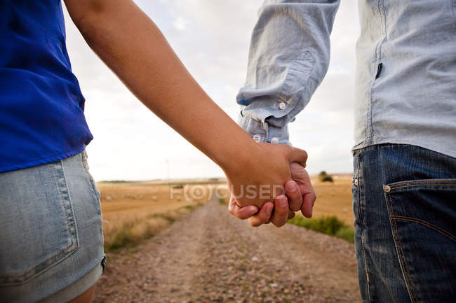 Casal de mãos dadas na estrada de terra — Fotografia de Stock