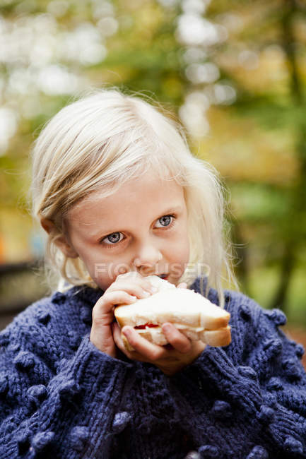 Girl eating sandwich in forest — Stock Photo