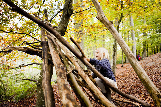 Menina fazendo barraca de madeira na floresta — Fotografia de Stock