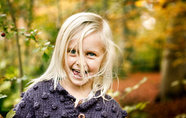 Chica con pelo rubio acariciado en el bosque - foto de stock