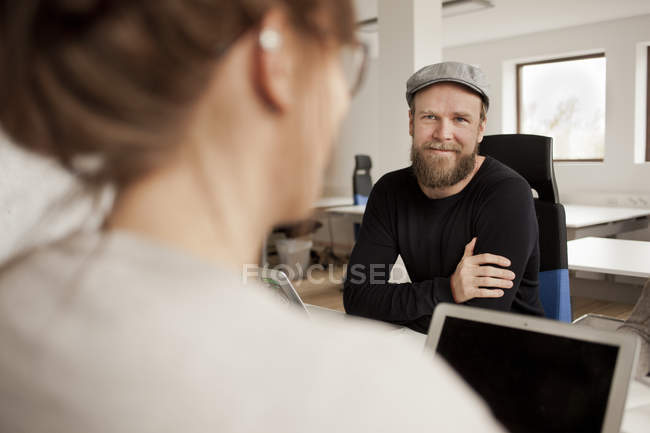 Man sitting with woman at desk — Stock Photo