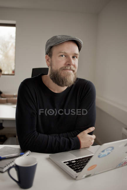 Hombre sentado en el escritorio en la oficina creativa - foto de stock