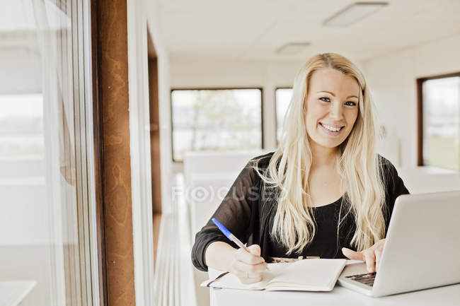 Businesswoman with laptop and note pad — Stock Photo