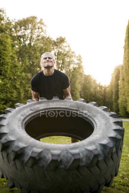 Junger Mann macht Reifen-Flip-Übung — Stockfoto