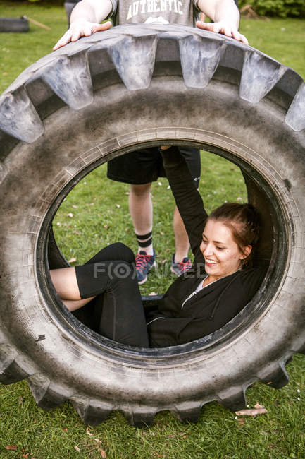 Mujer sonriente sentada en un neumático - foto de stock
