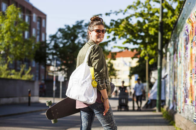 Mujer llevando monopatín - foto de stock