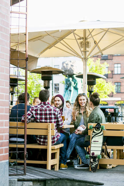 Друзья сидят в кафе на тротуаре — стоковое фото