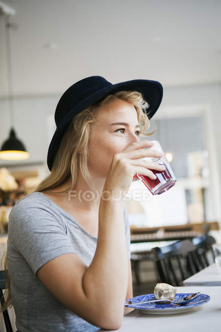 Jovem mulher tomando bebida — Fotografia de Stock