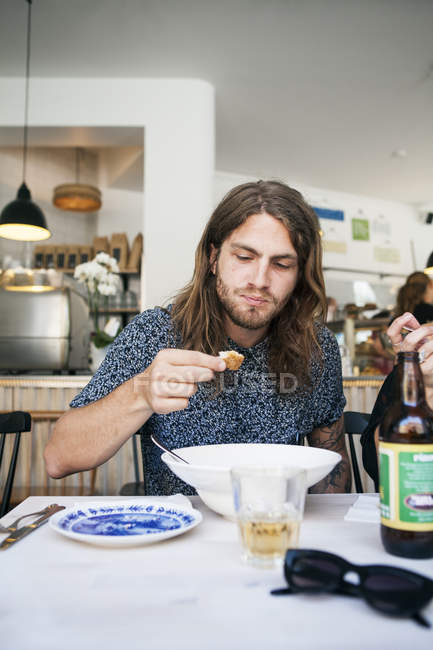 Young man having bread at table — Stock Photo