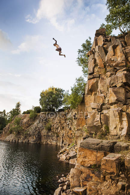 Hombre saltando en el lago - foto de stock