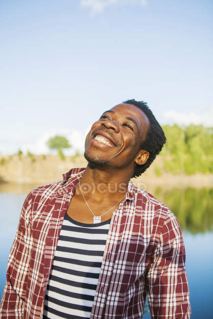 Man looking up while standing at lake shore — Stock Photo
