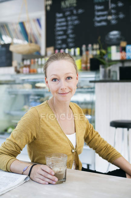 Femme assise à table dans un café — Photo de stock