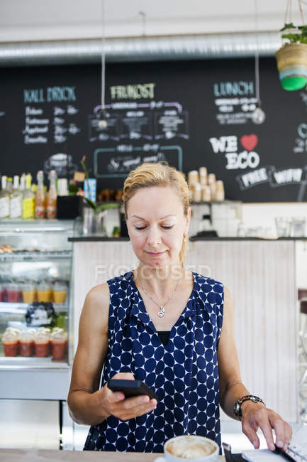 Donna che utilizza smartphone in caffetteria — Foto stock