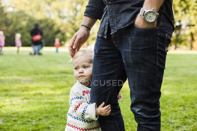Girl embracing fathers leg at park — Stock Photo