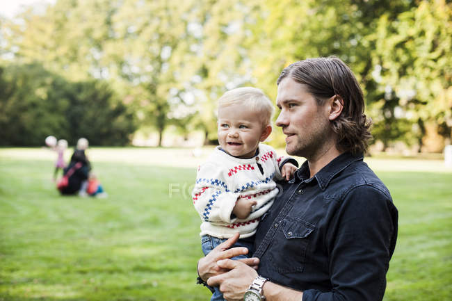 Hombre llevando bebé niña en parque - foto de stock