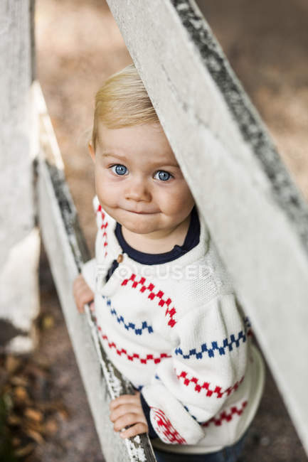 Baby girl standing at fence — Stock Photo