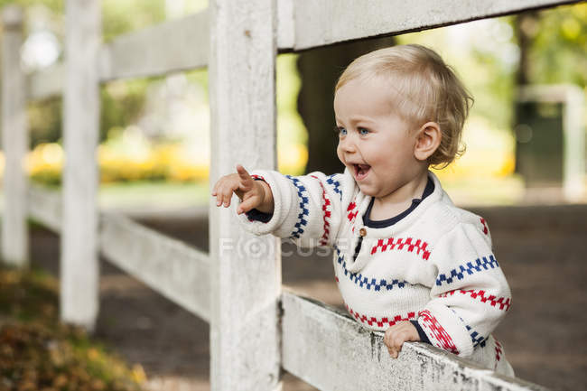 Baby girl pointing away at fence — Stock Photo