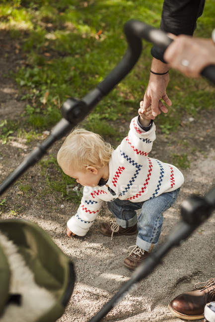 Baby girl bending while holding fathers hand — Stock Photo