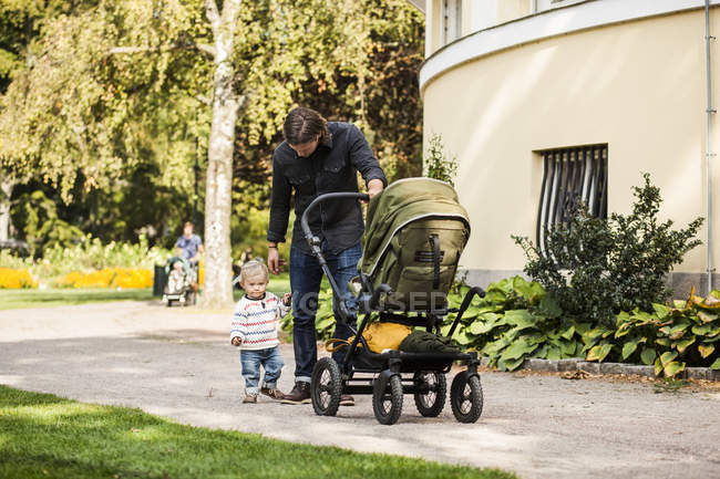 Pai e bebê andando com carruagem no parque — Fotografia de Stock