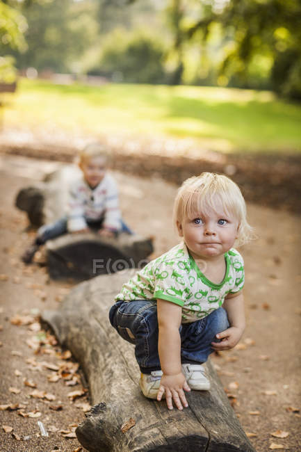 Baby boy crouching on log — Stock Photo