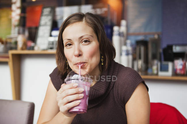 Woman drinking smoothie in cafe — Stock Photo