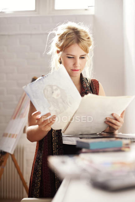 Female artist looking at paintings — Stock Photo