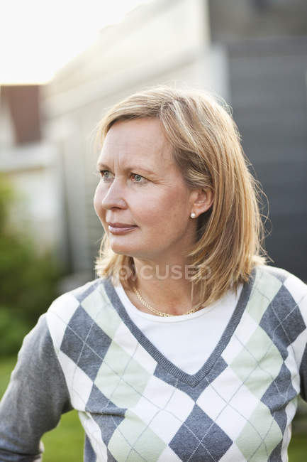 Woman looking away while standing in back yard — Stock Photo