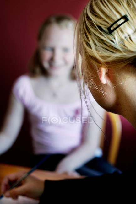 Vista cortada da mulher olhando para a menina desfocada enquanto escreve — Fotografia de Stock