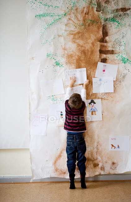 Menino colando papel na parede — Fotografia de Stock