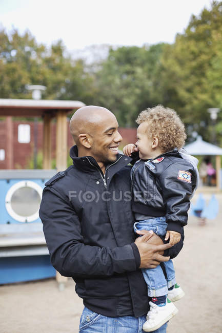 Padre che porta il figlio al parco giochi — Foto stock