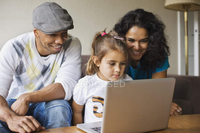 Отец и мать с дочерью с помощью ноутбука — стоковое фото