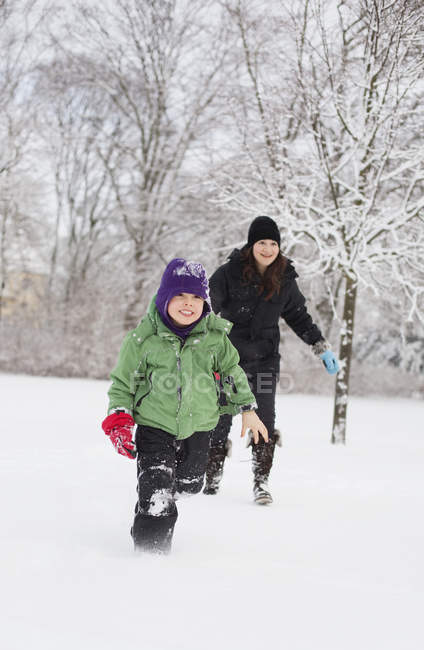Mère et fils courir sur le champ de neige — Photo de stock