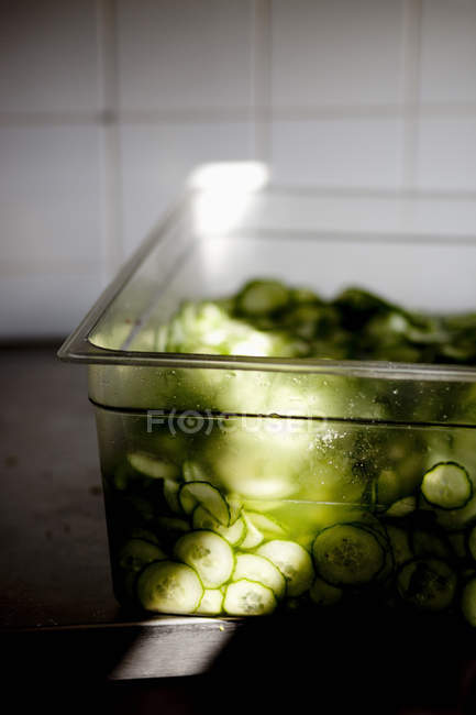 Sliced cucumbers in container — Stock Photo