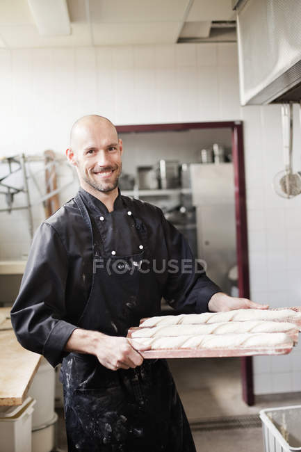 Chef holding baguette dough on baking sheet — Stock Photo