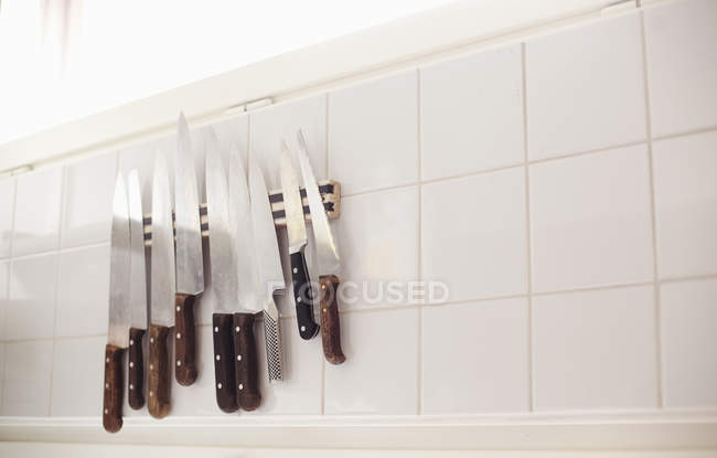Различные ножи на черепичной стене — стоковое фото