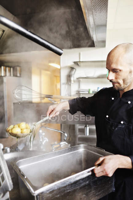 Шеф-повар жарит картошку в контейнере — стоковое фото