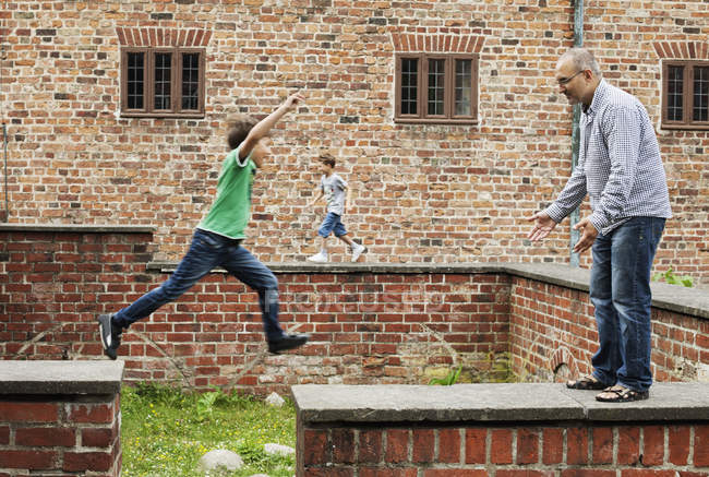 Junge springt über Stützmauer — Stockfoto