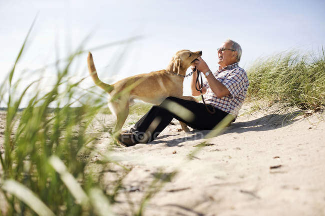 Uomo anziano che gioca con il cane — Foto stock