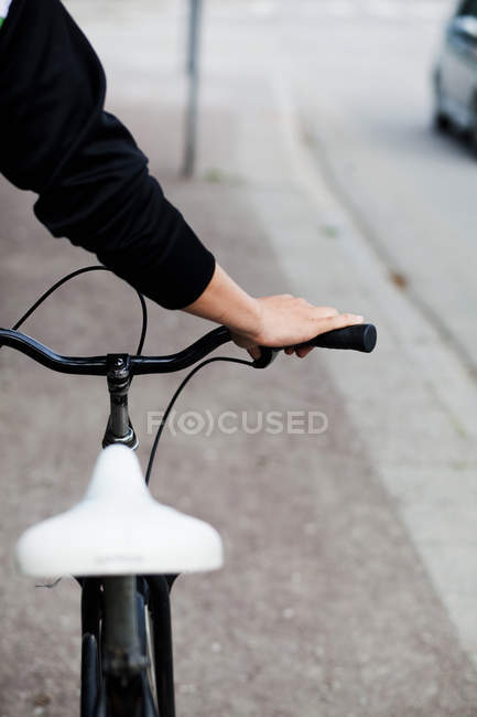 Hand holding bicycle in city — Stock Photo