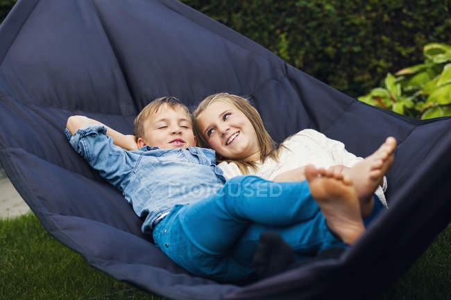 Happy siblings lying on hammock — Stock Photo