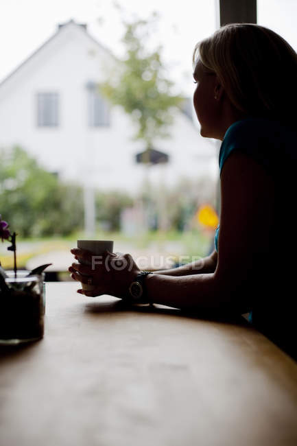 Femme réfléchie tenant tasse de café — Photo de stock