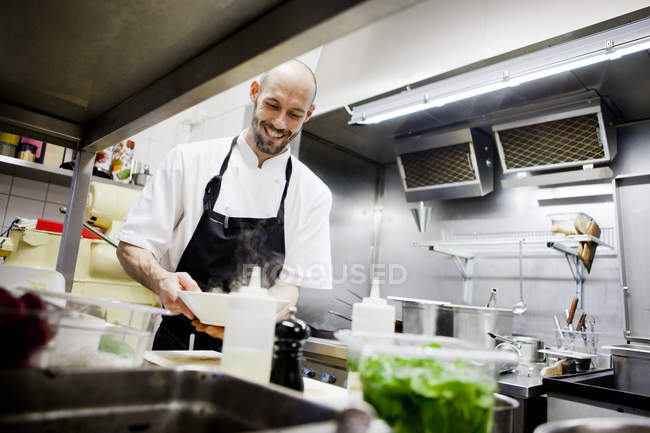 Chef tenant plat à la cuisine commerciale — Photo de stock