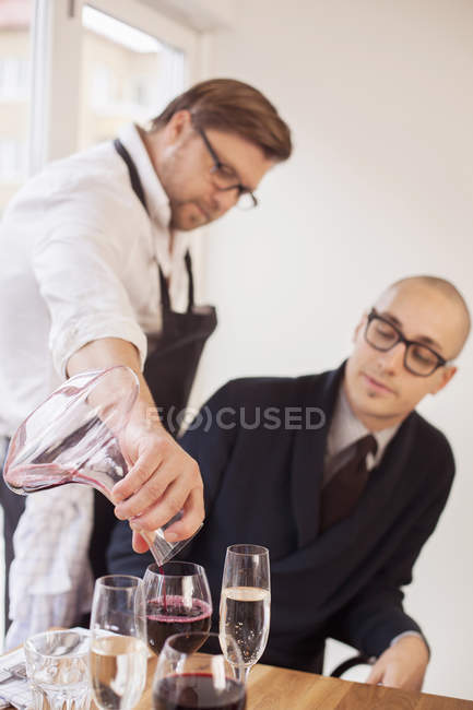 Chef sirviendo vino tinto al cliente - foto de stock