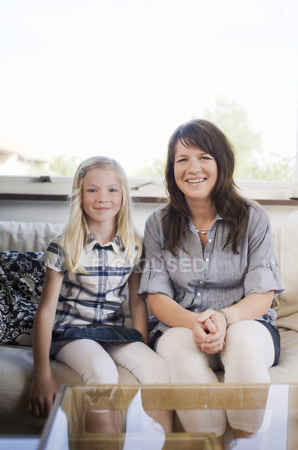 Mother and daughter sitting together on sofa at home — Stock Photo