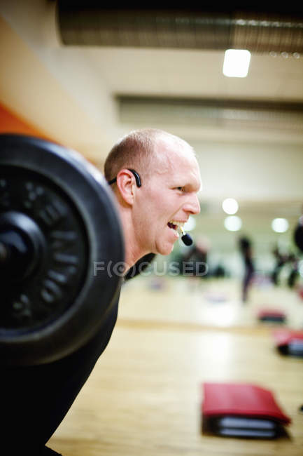 Cheerful instructor lifting barbell — Stock Photo